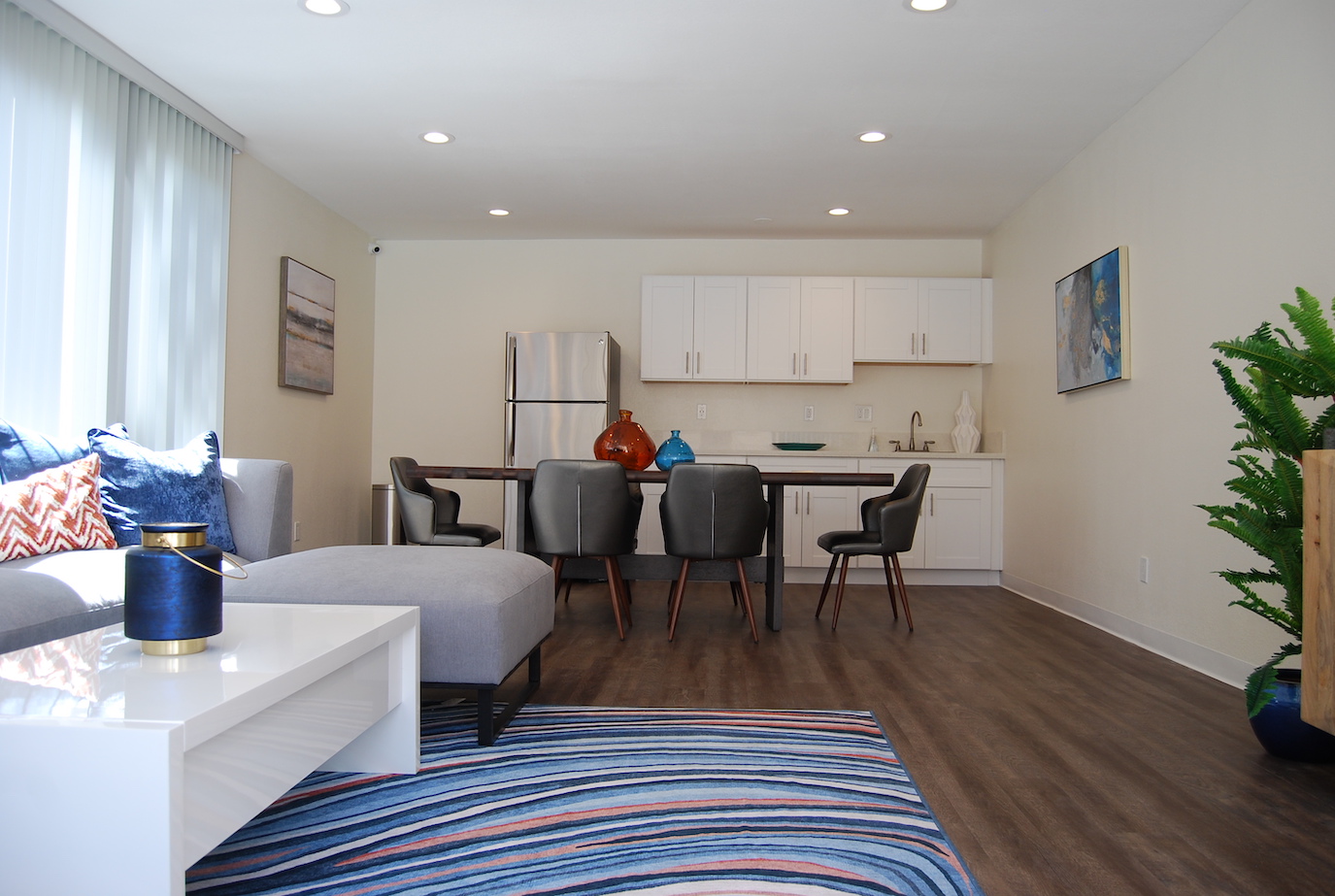 Community clubhouse, looking in at the couch, dining table and kitchenette.