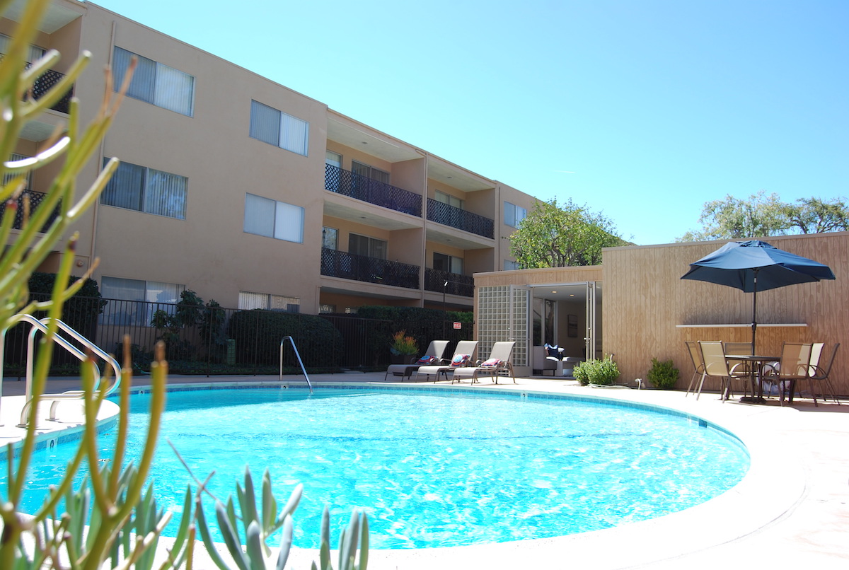 The sparkling community pool with the clubhouse and lounge area in the back.