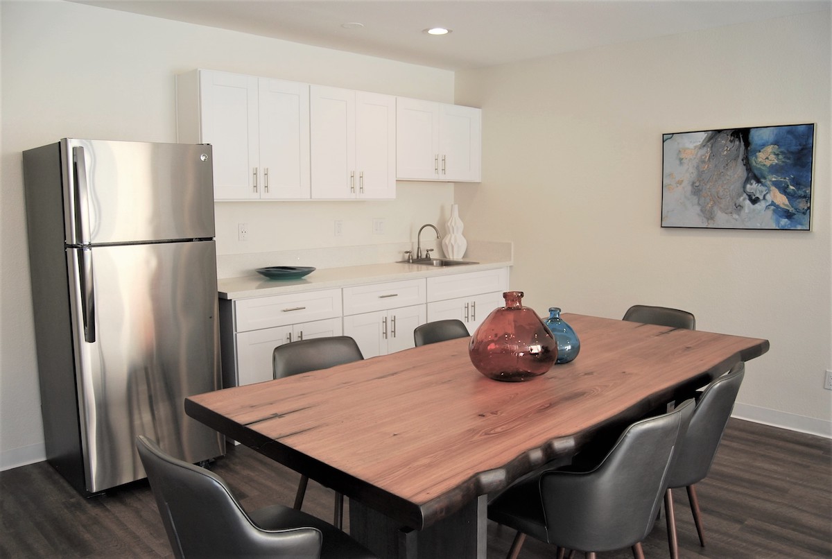 Community clubhouse, dining table, stainless steel fridge and kitchenette.