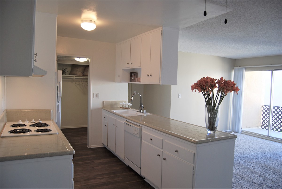 Kitchen featuring porcelain countertops, overhead cabinets, wood-inspired flooring and contemporary appliances, second view.